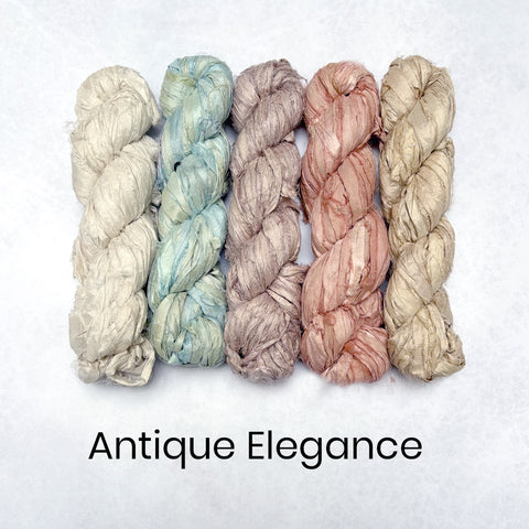A collection of recycled sari silk ribbons in various shades of pink, purple, beige, brown, and red, arranged side by side on a neutral background.