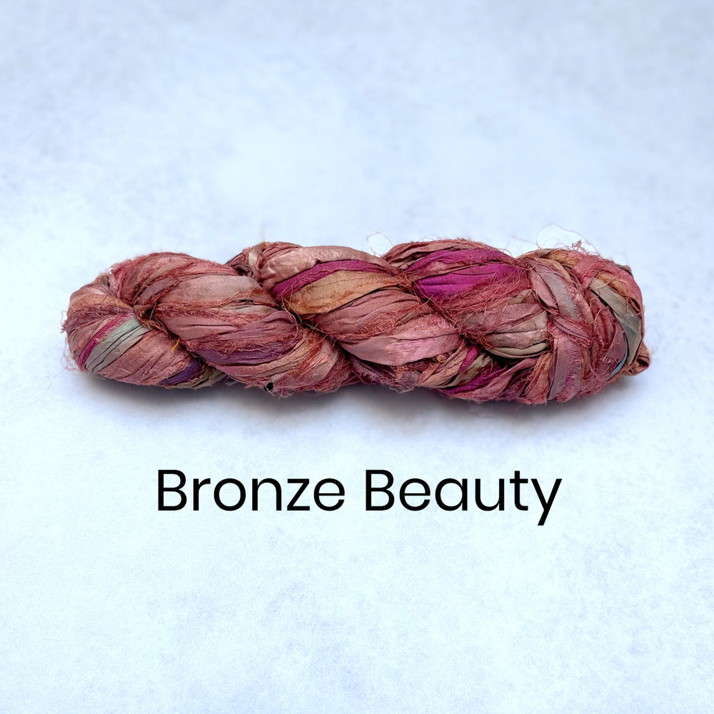 Autumn coloured Braided sari silk strips with pink and bronze tones on a light blue background, labeled 'Bronze Beauty'.
