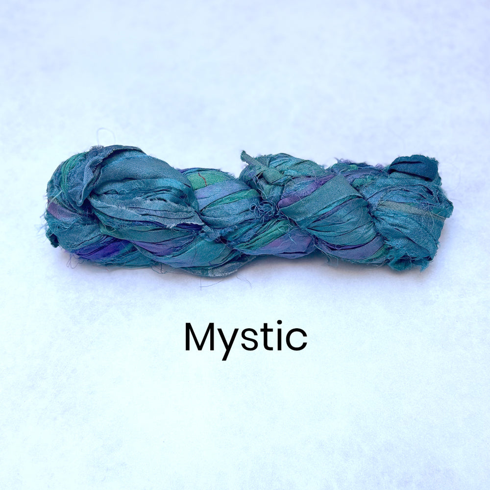 Braided teal and purple sari silk ribbon strips of fabric / yarn on a white background with 'Mystic' text.