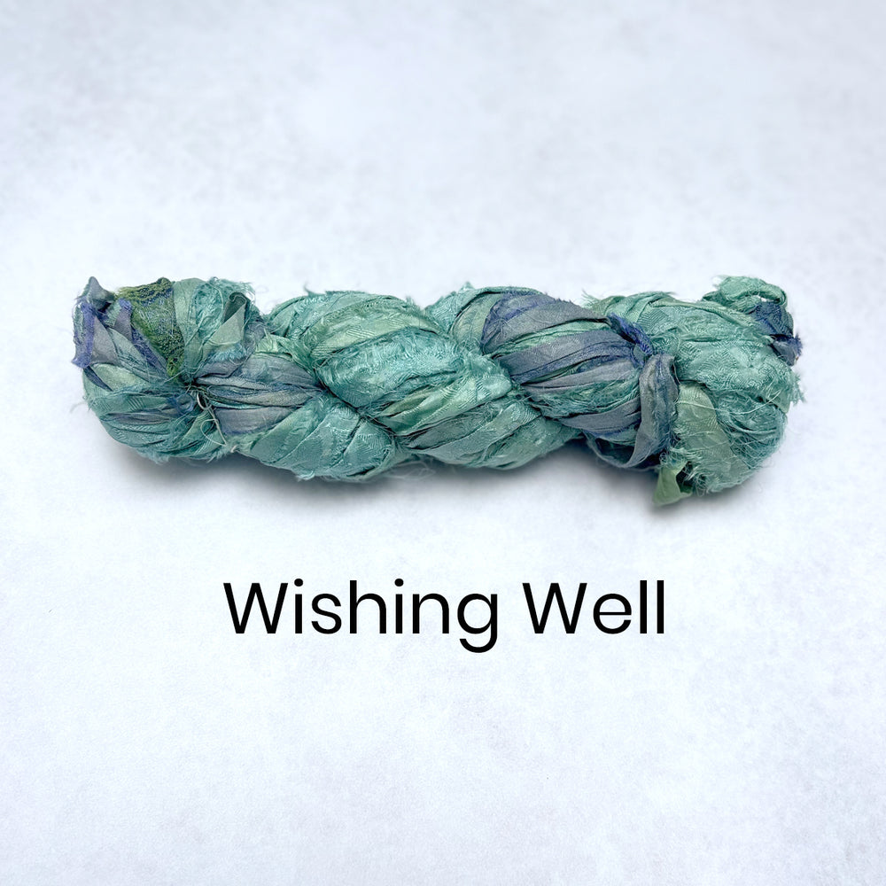 Plait of silk fabric strips tied into a braided skein for textile crafts in blue colours. 