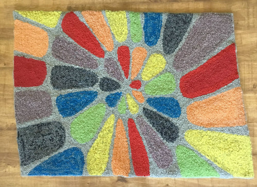 Colorful rainbow spiral design rag rug with a geometric pattern on a wooden floor