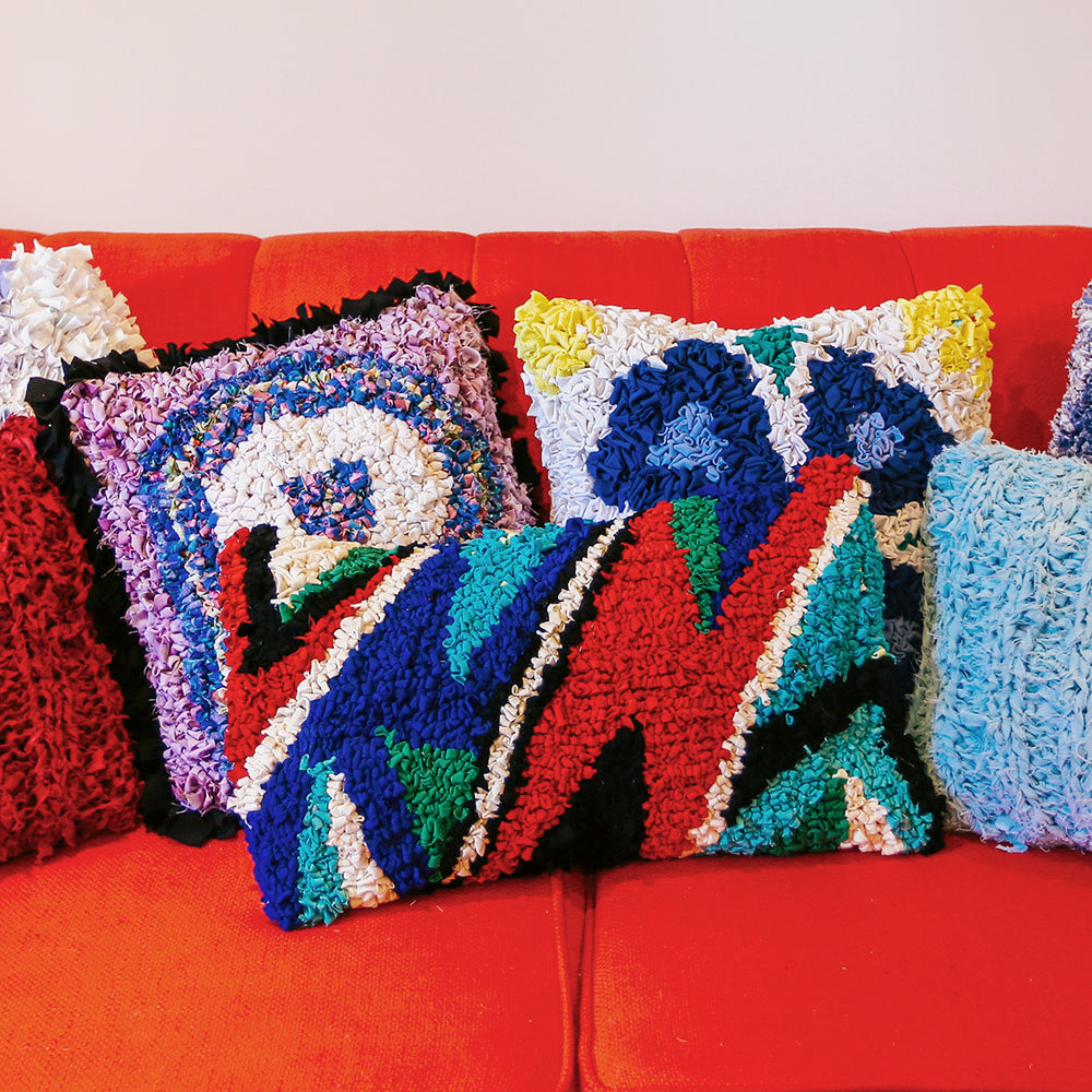Group of colourful rag rug cushions on a red sofa