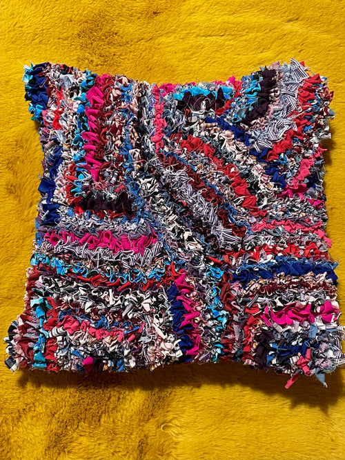 Multicoloured short shaggy rag rugged cushion with recycled fabrics on a yellow background