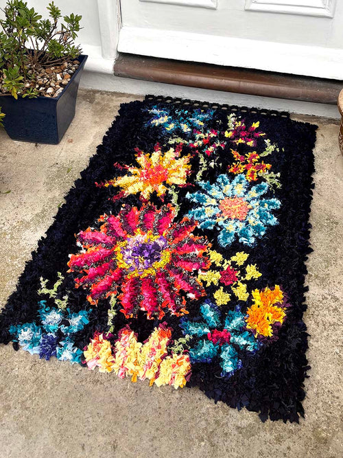 Colorful floral-patterned rug on a concrete floor outside a building.