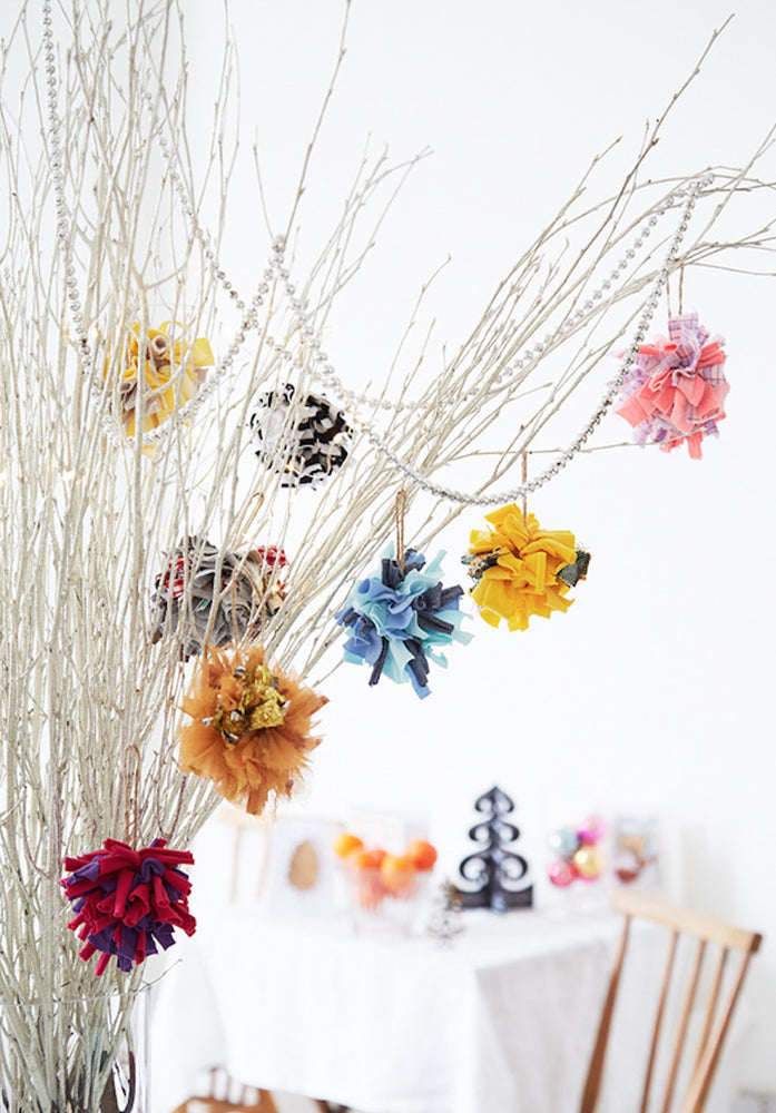 Festive handmade colourful shaggy rag rug Christmas hanging bauble decoration inside on a white tree