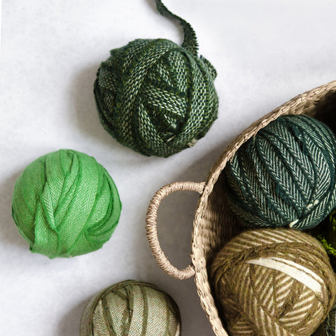 A selection of green Wool Blanket Selvedge Edges balled up for rag rug making - Ragged Life Blanket Yarn