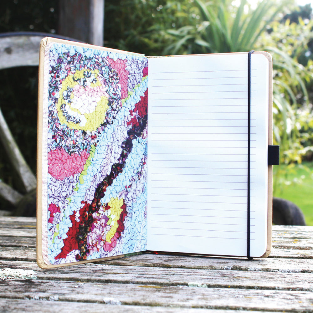 Ragged Life hardback notebook open with lined paper and a colourful loopy rag rug image