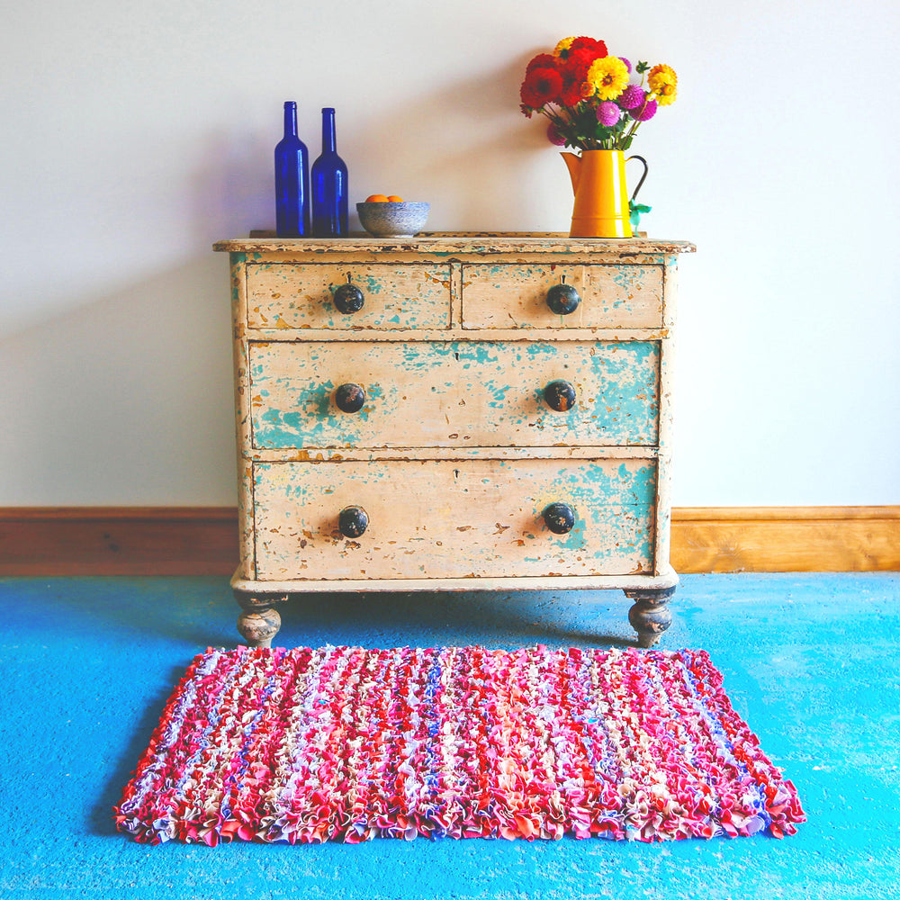 Pinky shaggy striped handmade rag rug on blue floor with flowers
