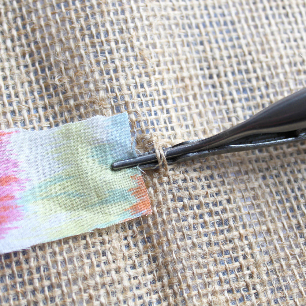 Rag Rug Spring Tool gripping onto a fabric strip in the hessian rug