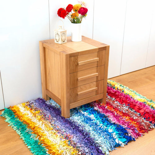 Shaggy rag rug with a colourful rainbow stripe pattern displayed inside on a wooden floor